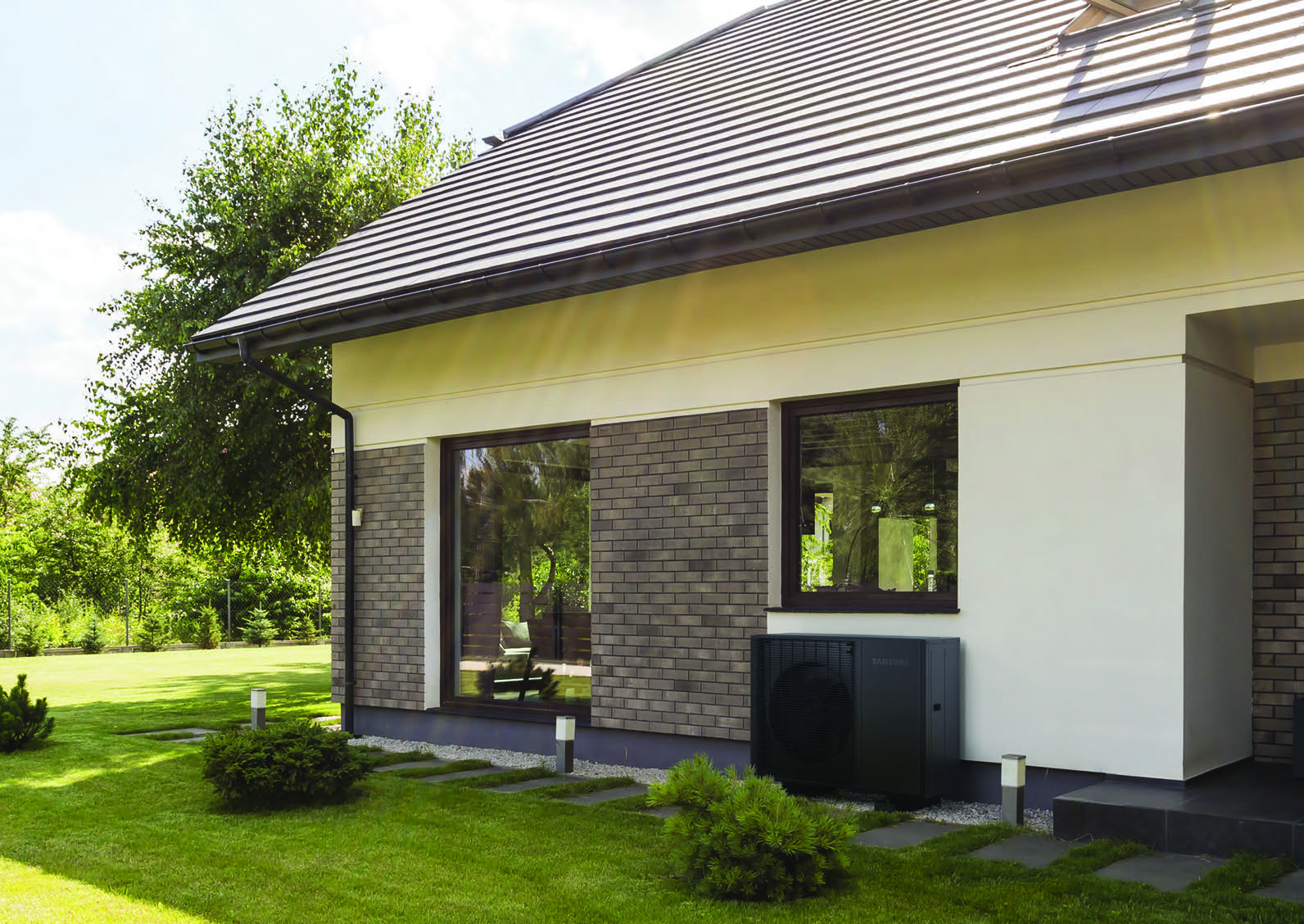 Wärmepumpe an einem Haus mit grünem Garten